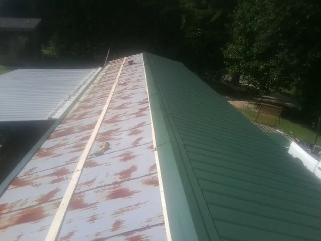 Old rusted panels beside newly installed green metal roofing — Wind Damage Roof Repair by Roofing Brothers in Luthersville