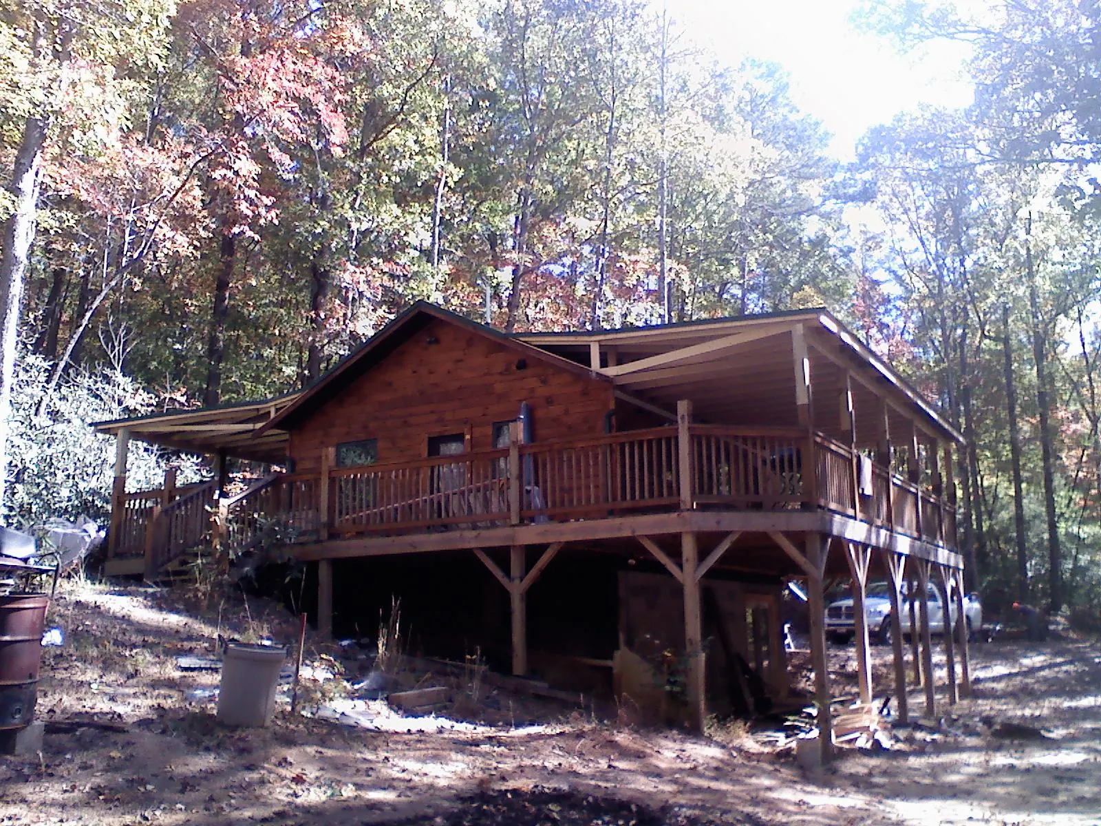 Log cabin with a wraparound porch and metal roof in the fall in Luthersville