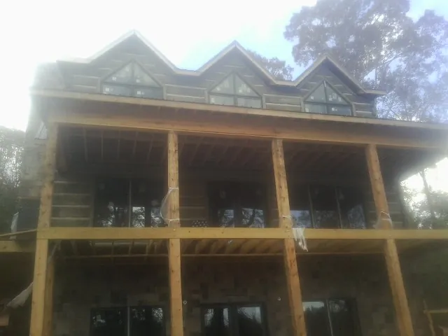 Dormers and porch framing on a large log home under construction — Roof Coating work by our crew in Luthersville