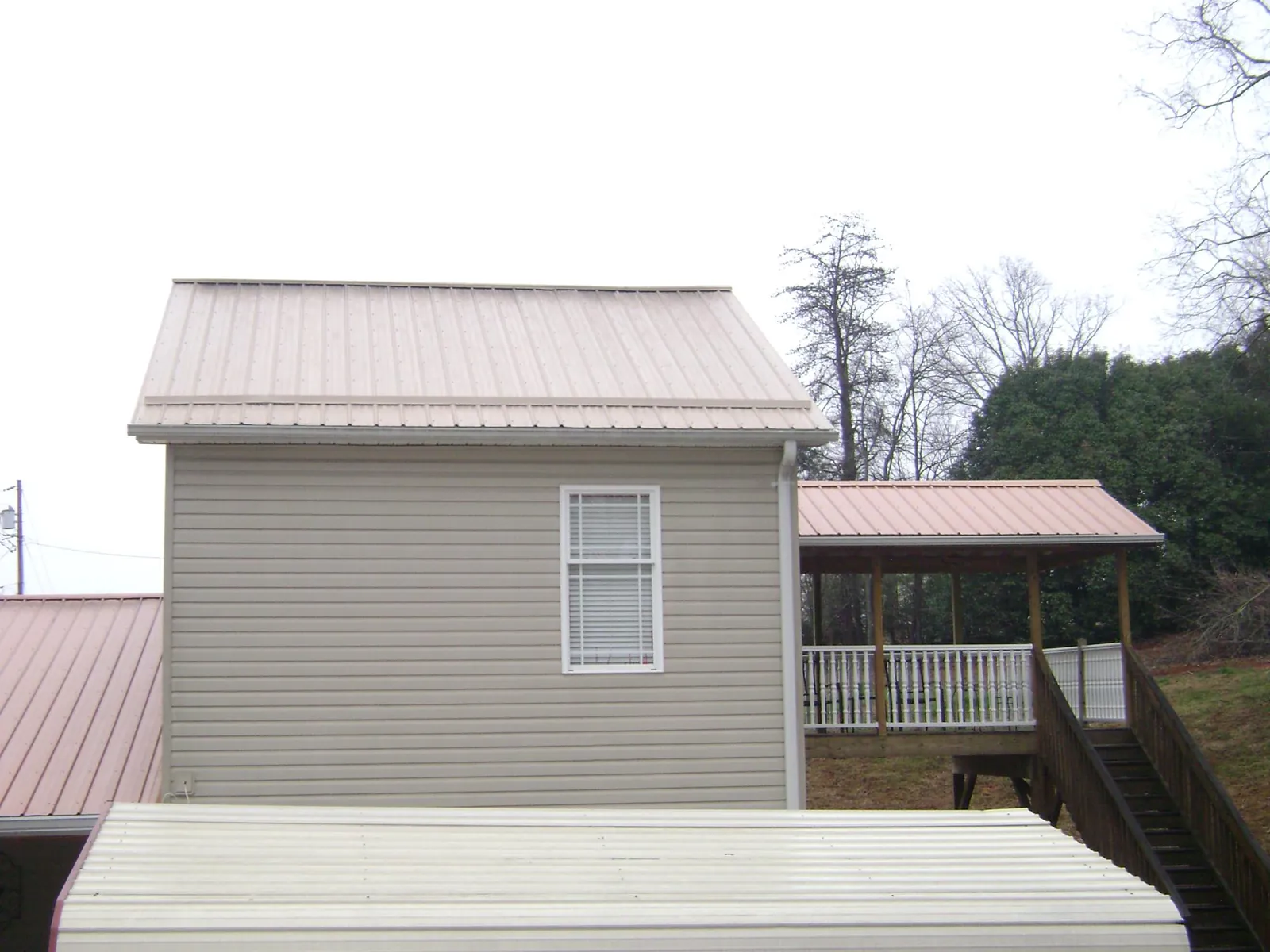 Tan metal roofs on a two story addition and attached porch, from a Roof Replacement job in Luthersville