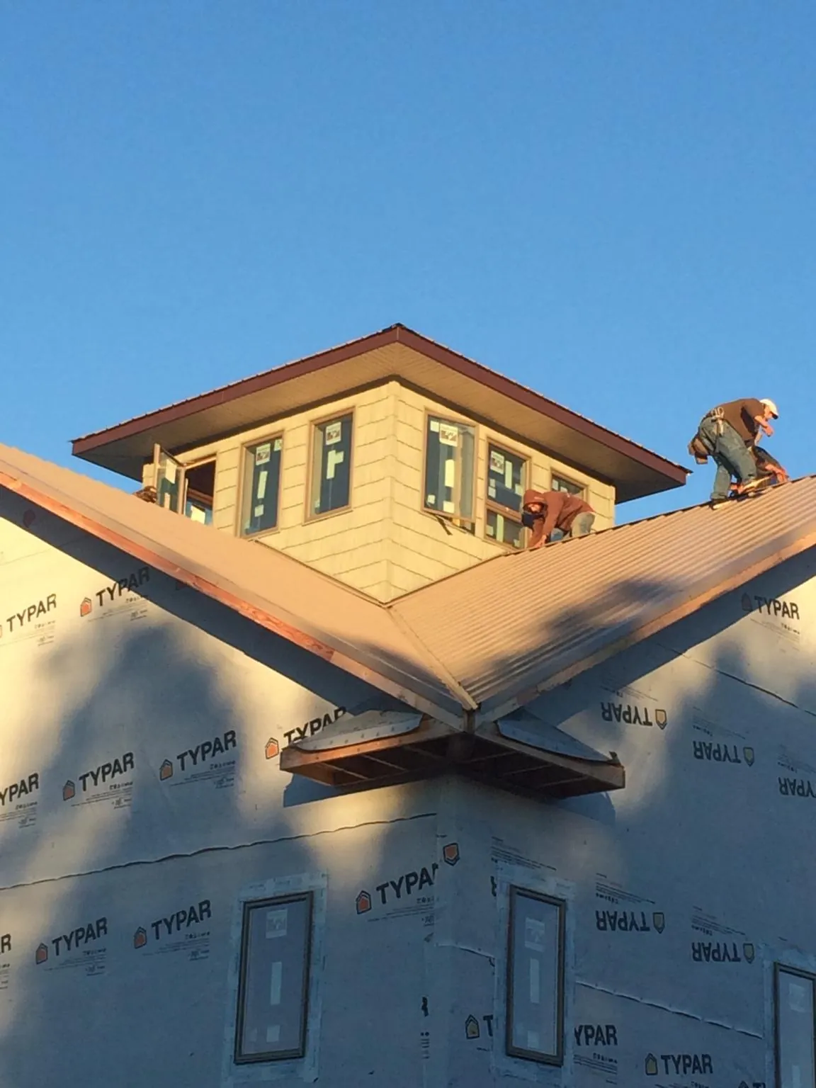 Roofers working around a rooftop cupola on a new metal roof at sunset — Roof Waterproofing in Luthersville by Roofing Brothers